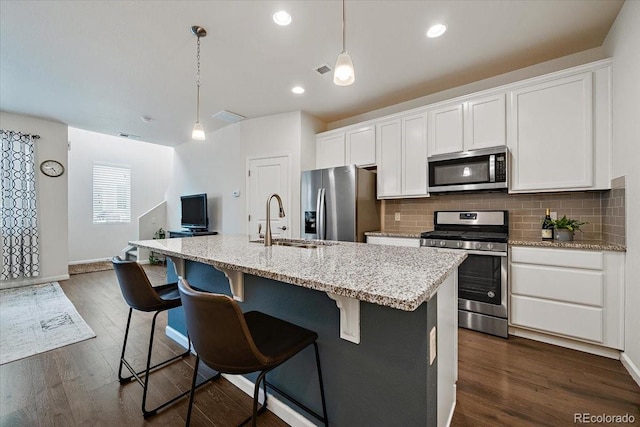 kitchen featuring white cabinetry, appliances with stainless steel finishes, a kitchen island with sink, and pendant lighting