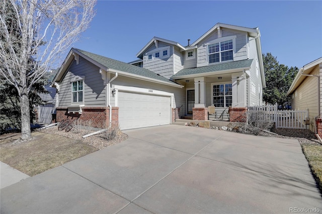 craftsman house with a garage, driveway, a shingled roof, fence, and brick siding