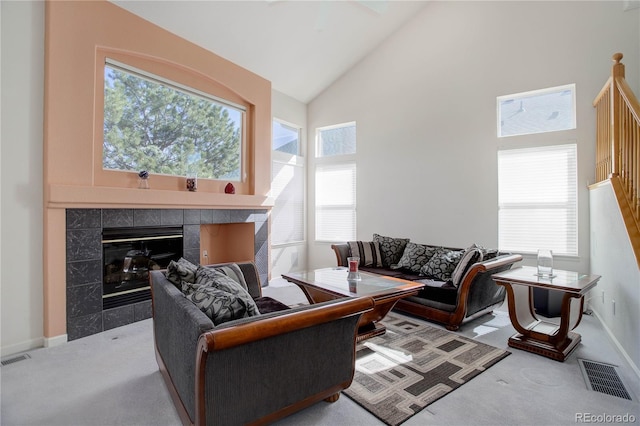 living room with a wealth of natural light, a tiled fireplace, carpet flooring, and visible vents