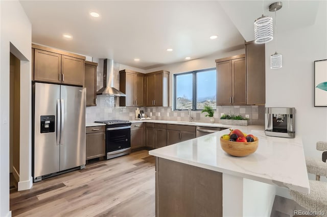 1103 Lupine Ln, Tabernash, CO 80478 - kitchen with light wood-type flooring, a sink, wall chimney range hood, a peninsula, and appliances with stainless steel finishes