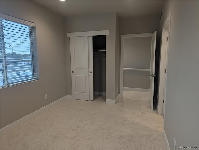 unfurnished bedroom with light colored carpet and a closet