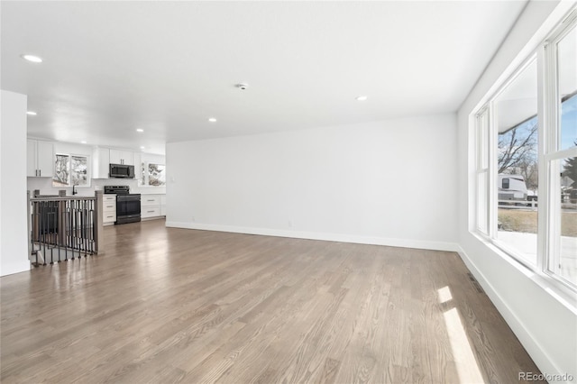 living area featuring light wood-style floors, baseboards, and recessed lighting