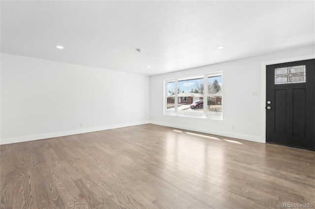 interior space with baseboards, wood finished floors, and recessed lighting