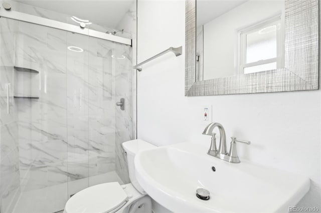 full bathroom featuring a marble finish shower, a sink, and toilet