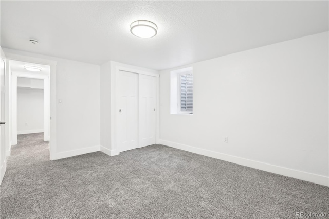 unfurnished bedroom featuring carpet, a closet, baseboards, and a textured ceiling