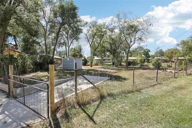 view of yard with a storage shed, a gate, fence, and an outdoor structure