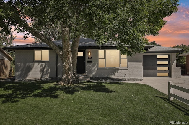 view of front of house featuring a garage, a front yard, concrete driveway, and brick siding