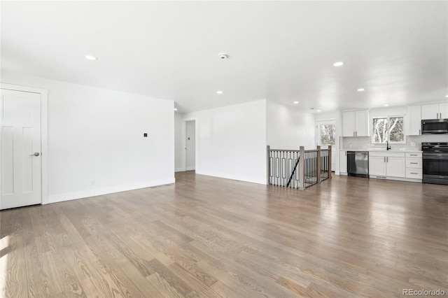 unfurnished living room featuring light wood-style floors, recessed lighting, a sink, and baseboards