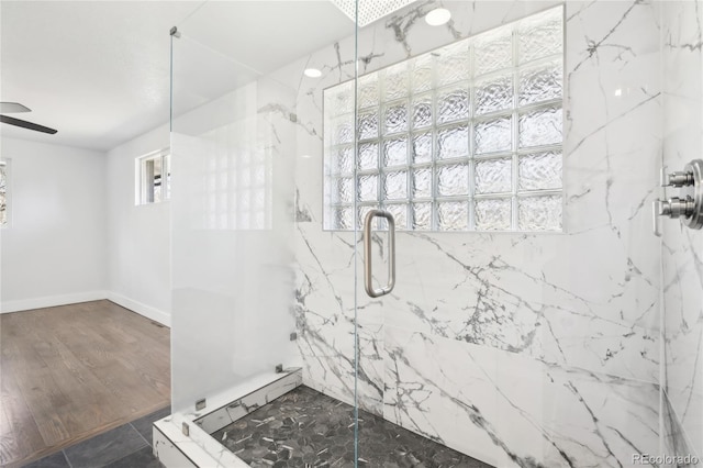 full bathroom featuring ceiling fan, a marble finish shower, baseboards, and wood finished floors