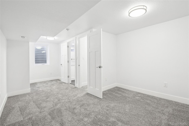 below grade area with a textured ceiling, carpet, visible vents, and baseboards