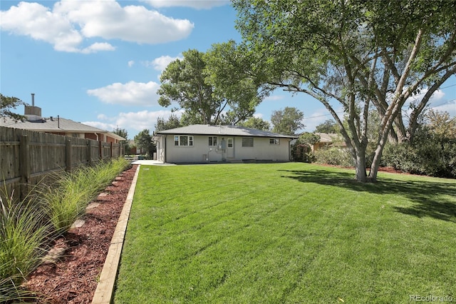 back of property featuring a yard and fence