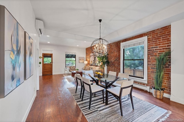 dining space featuring dark wood-type flooring, a chandelier, a wall unit AC, and brick wall