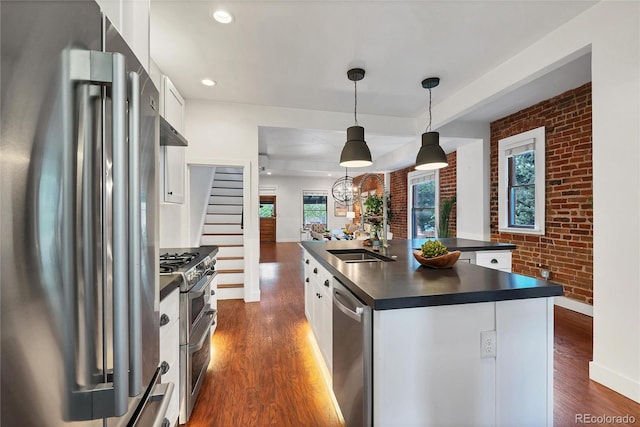 kitchen with dark hardwood / wood-style flooring, white cabinets, an island with sink, sink, and high end appliances