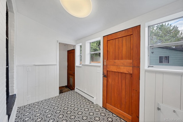 tiled foyer featuring lofted ceiling, a baseboard radiator, and a wealth of natural light