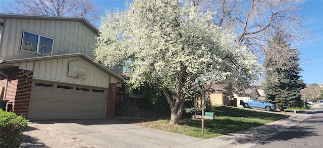 view of front of property featuring board and batten siding, brick siding, and concrete driveway