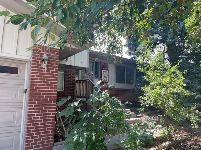 view of exterior entry featuring brick siding and a garage