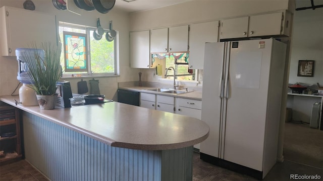 kitchen with a sink, light countertops, freestanding refrigerator, a peninsula, and black dishwasher