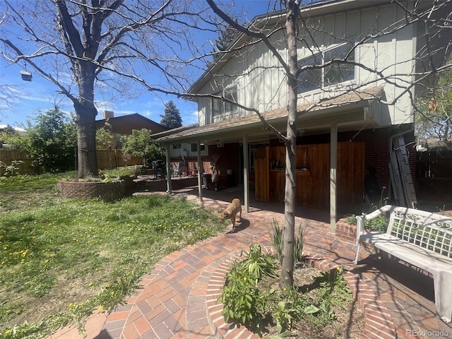 back of property with fence, a patio area, and a lawn