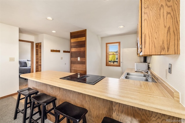 9430 Ryan Gulch Rd Unit 9450, Silverthorne, CO 80498 - kitchen featuring a sink, a peninsula, black electric stovetop, recessed lighting, and a breakfast bar