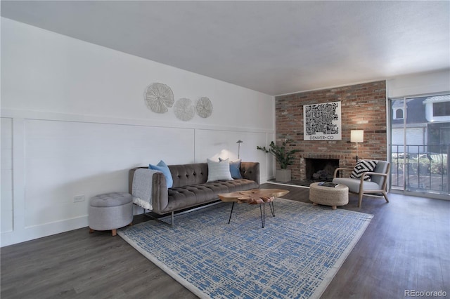 living room with a brick fireplace and dark hardwood / wood-style flooring