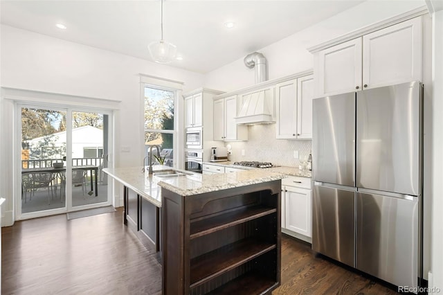 kitchen featuring appliances with stainless steel finishes, light stone counters, sink, pendant lighting, and white cabinets