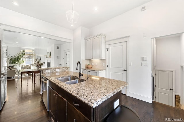 kitchen featuring a center island with sink, sink, hanging light fixtures, dark hardwood / wood-style flooring, and white cabinetry