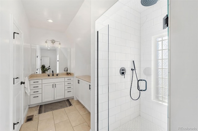 bathroom featuring tile patterned flooring, vanity, and a tile shower