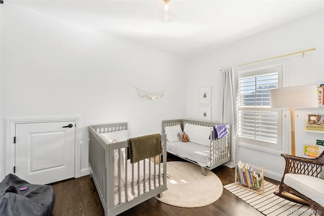 bedroom featuring dark hardwood / wood-style flooring and a nursery area