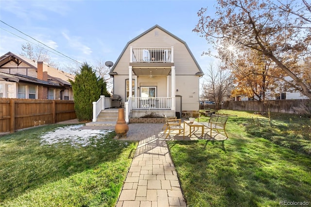 back of house featuring a lawn, a balcony, and a patio