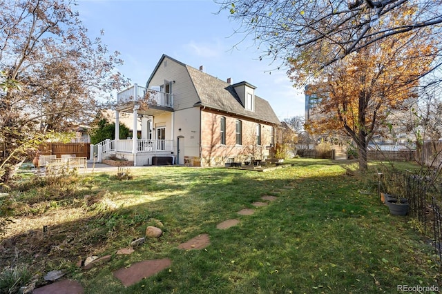 rear view of house with a yard and a balcony