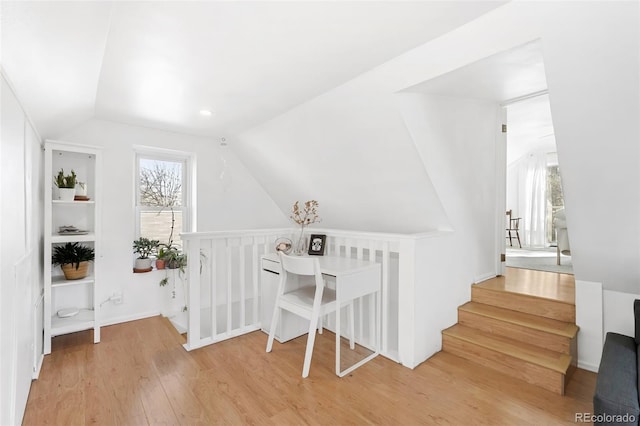 home office featuring hardwood / wood-style floors, built in features, and lofted ceiling