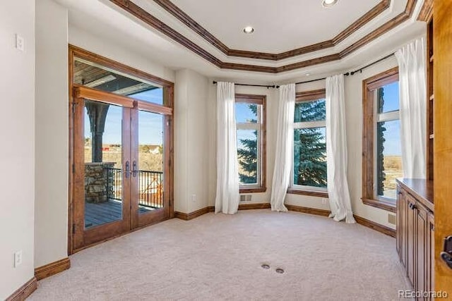 carpeted empty room with french doors, ornamental molding, and a tray ceiling