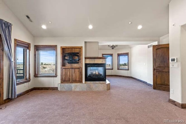 unfurnished living room with an inviting chandelier, a multi sided fireplace, vaulted ceiling, and carpet