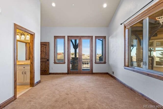 empty room with high vaulted ceiling and light colored carpet