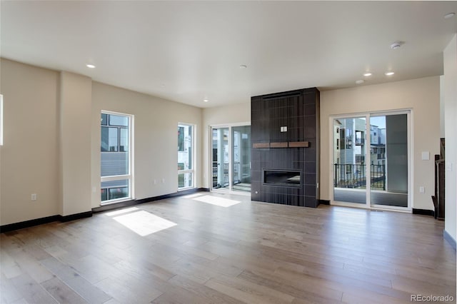 unfurnished living room featuring baseboards, a fireplace, wood finished floors, and recessed lighting