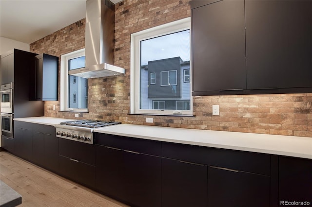 kitchen with stainless steel gas stovetop, light countertops, modern cabinets, light wood-style floors, and wall chimney range hood
