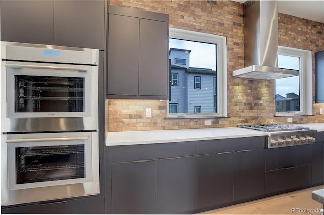 kitchen featuring light countertops, exhaust hood, stainless steel appliances, gray cabinetry, and modern cabinets