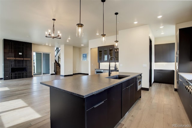 kitchen with modern cabinets, recessed lighting, an island with sink, a sink, and light wood-style floors
