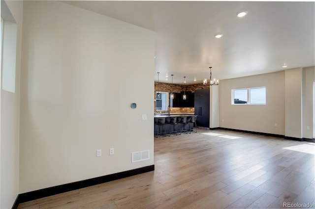 unfurnished living room featuring visible vents, a chandelier, light wood finished floors, baseboards, and recessed lighting