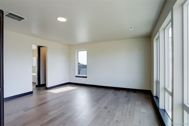 spare room featuring wood finished floors, baseboards, and visible vents