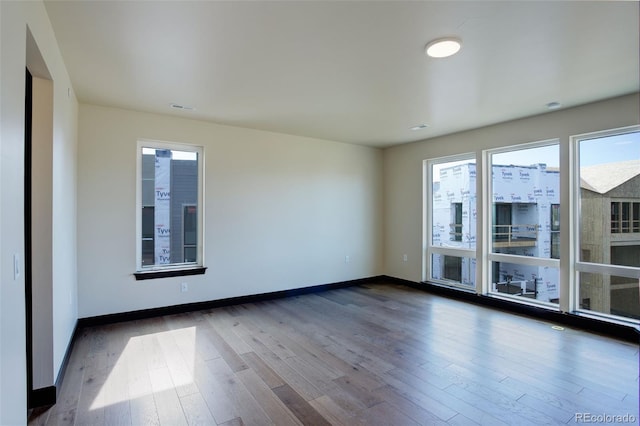 spare room with baseboards, dark wood-style floors, and visible vents