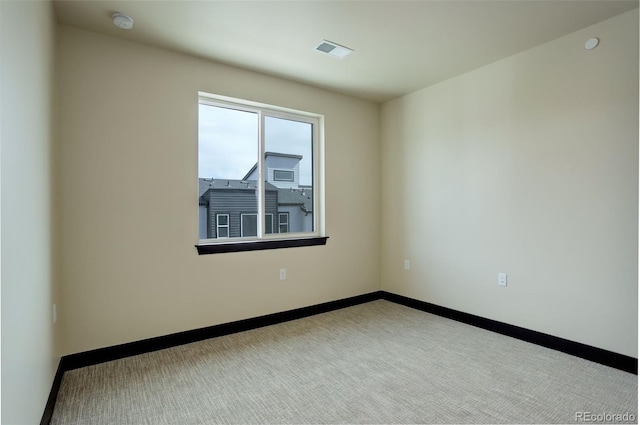 carpeted empty room featuring baseboards and visible vents
