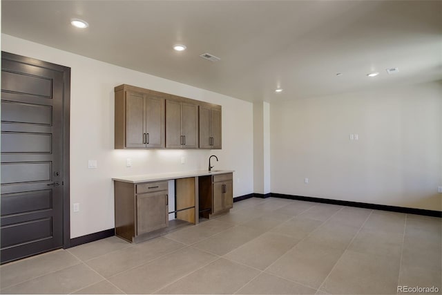 kitchen featuring light countertops, a sink, baseboards, and recessed lighting