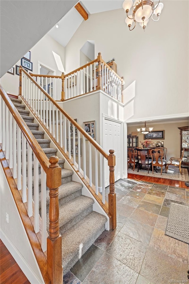 stairway featuring hardwood / wood-style flooring, a chandelier, and high vaulted ceiling