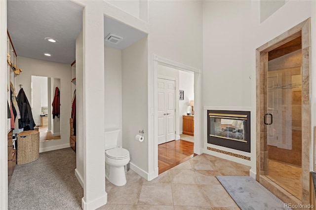 bathroom featuring toilet, tile patterned floors, and a shower with door