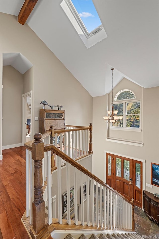 stairs with hardwood / wood-style floors, beamed ceiling, an inviting chandelier, and high vaulted ceiling