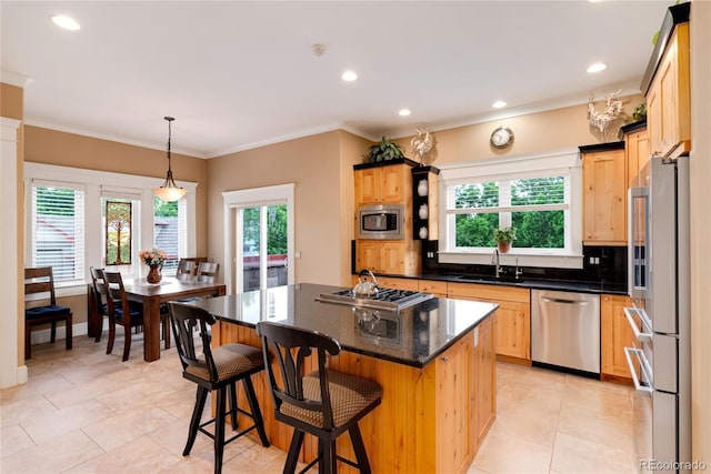 kitchen with sink, tasteful backsplash, decorative light fixtures, appliances with stainless steel finishes, and a kitchen island