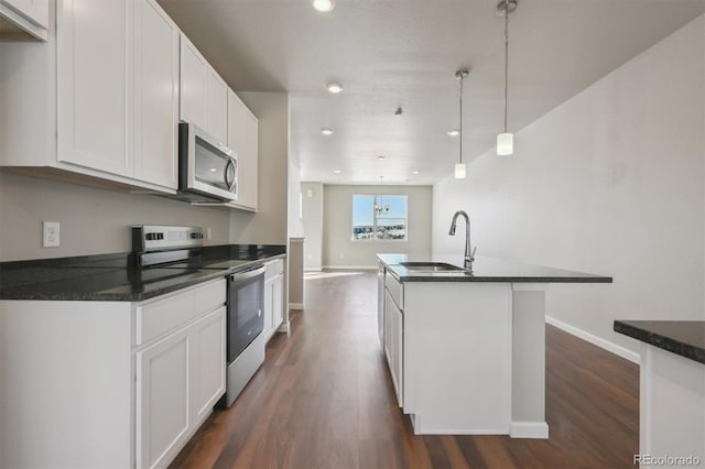 kitchen with an island with sink, sink, white cabinets, hanging light fixtures, and stainless steel appliances