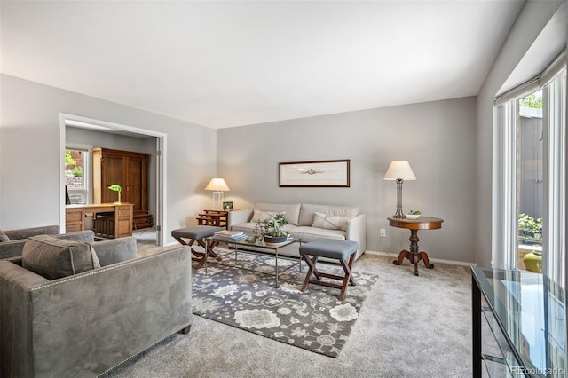 carpeted living area featuring healthy amount of natural light and baseboards