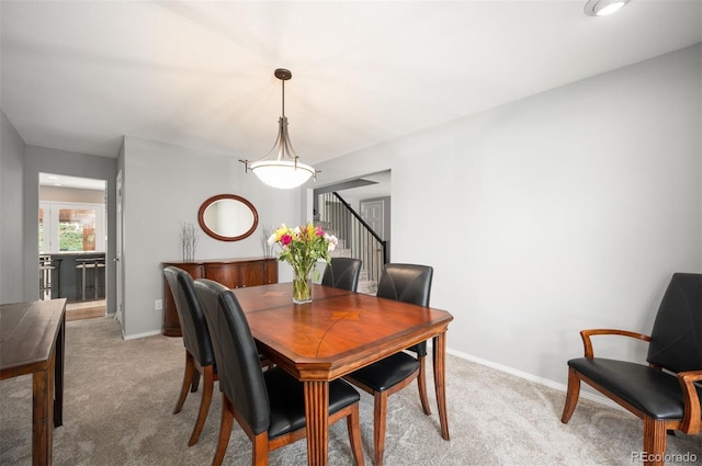dining area with stairs, light colored carpet, and baseboards